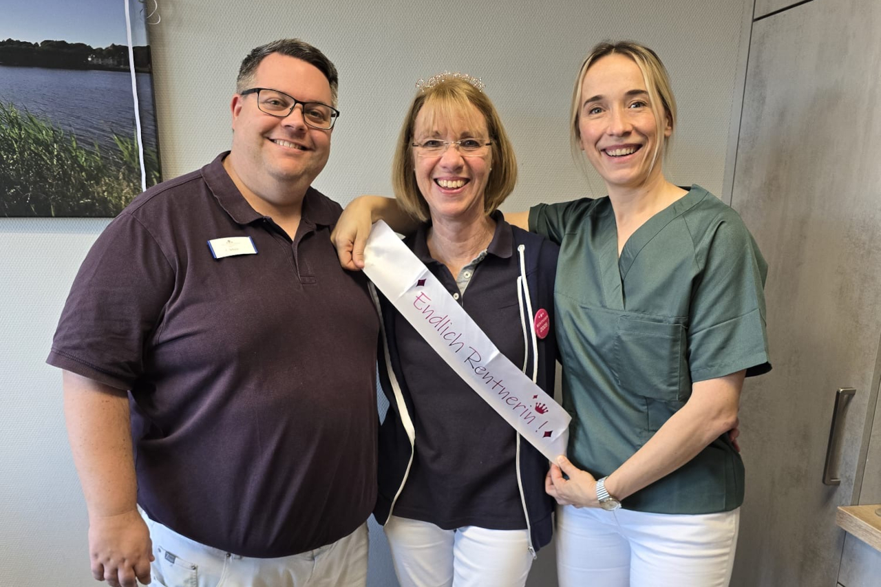 Birgit Sievers zwischen den Ärzten Christian Schulz und Male Müller. Frau Müller trägt eine Schärpe, auf der steht: "Endlich Rentnerin"